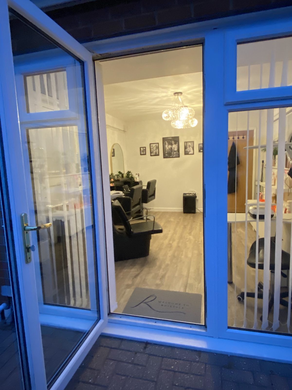 The salon entrance: a blue-framed glass door open onto the salon, with an R doormat