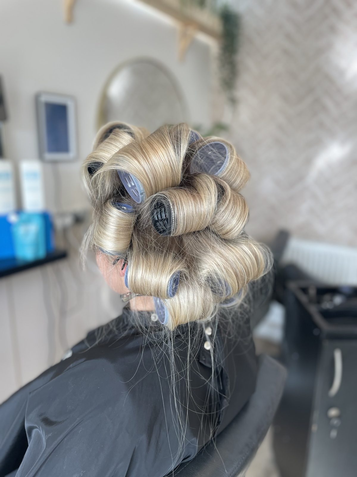 Blonde hair set in large rollers at the styling station