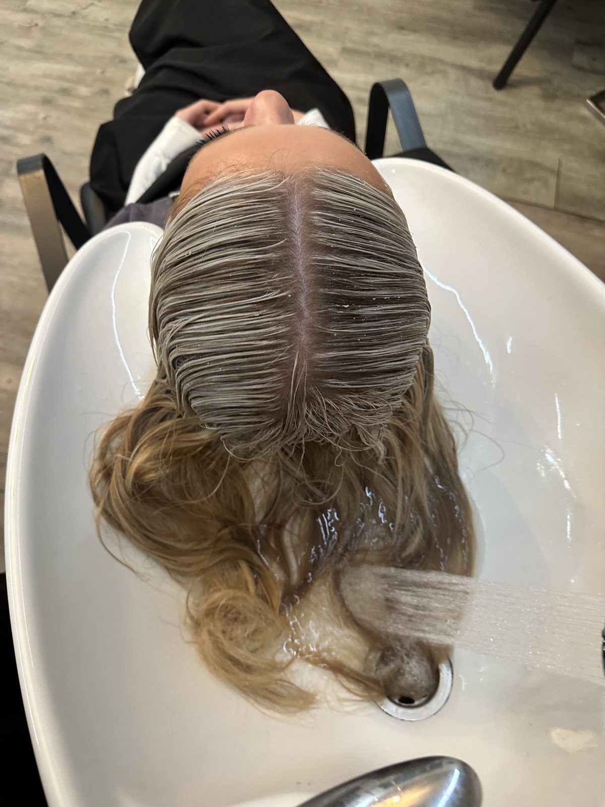 Toned blonde hair being rinsed at the backwash basin